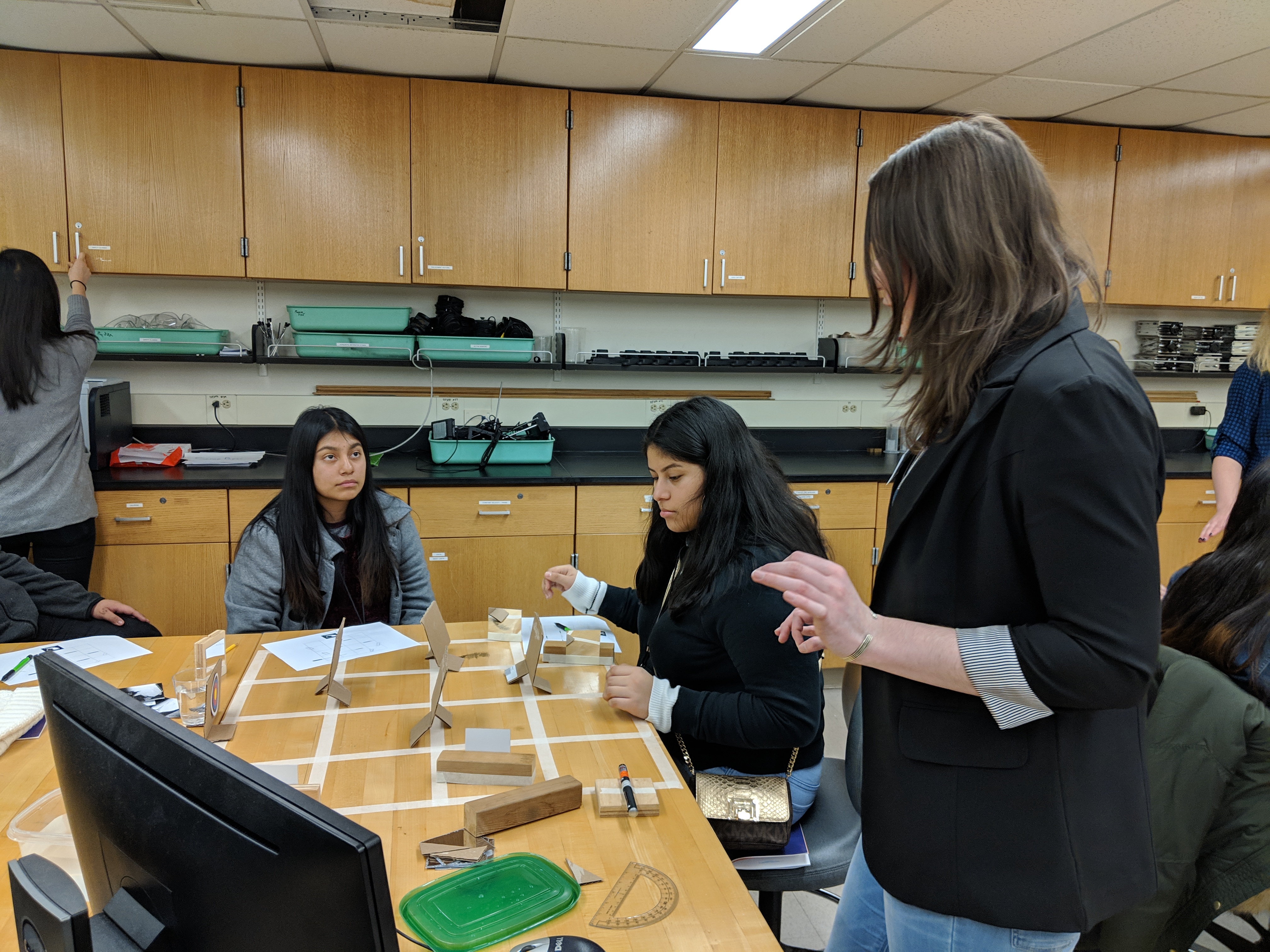 Madelyn advises a group of high schoolers on an optics outreach activity.