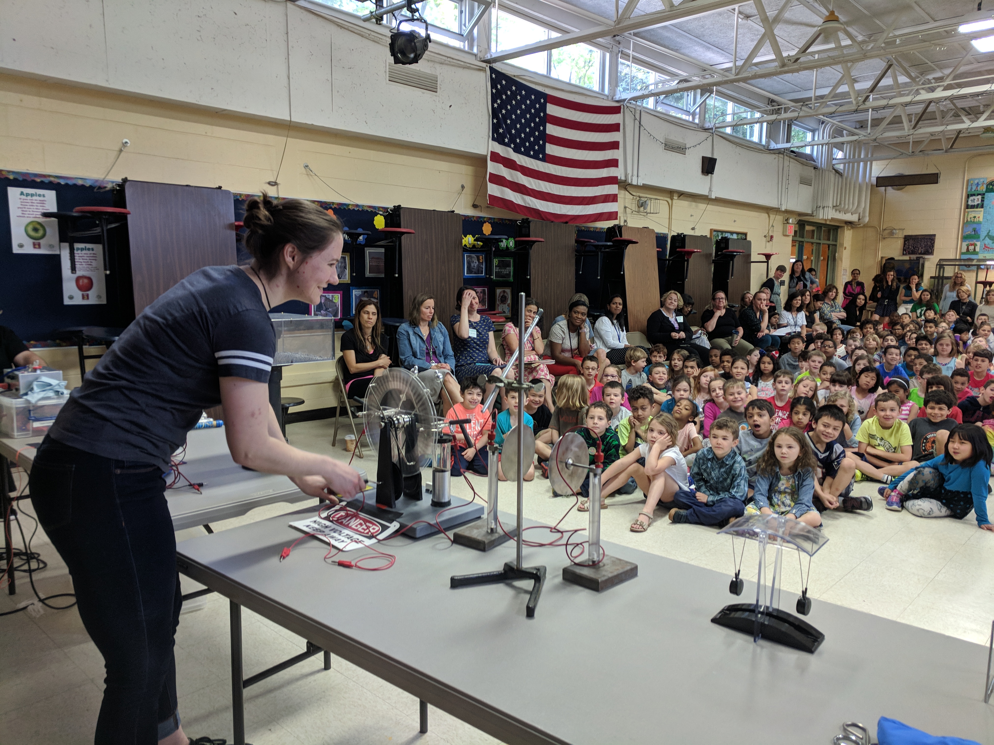 Madelyn performs physics demo to large group of seated elemetary schoolers.