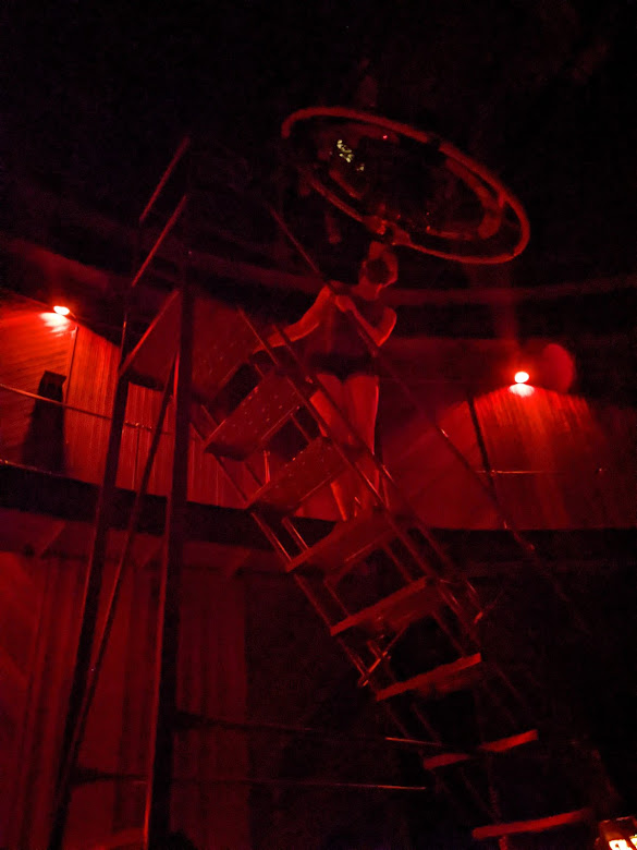 Madelyn, illuminated by red light, on a ladder looking through Lick Observatory's 36 inch refracting telescope.